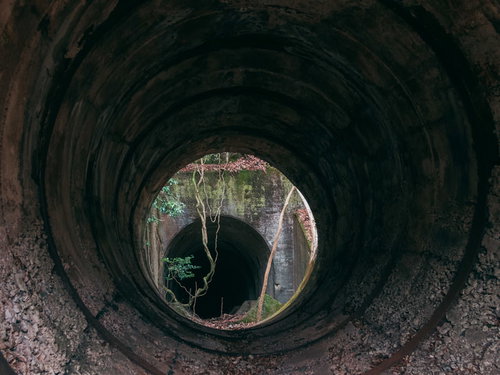 穴の先に見えるコンクリート製トンネルと遺構