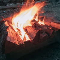 白く立ち上がる炎に包まれた薪のキャンプファイヤーの写真