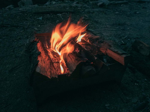 暗闇で赤く燃え上がるキャンプファイヤーの焚き火
