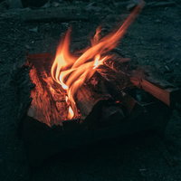 キャンプ中の焚火で燃え上がる薪と炎の迫力ある風景の写真