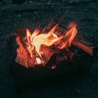 赤く揺らめくキャンプファイヤーの炎と薪が燃え上がる様子の写真