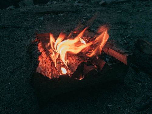 赤く揺らめくキャンプファイヤーの炎と薪が燃え上がる様子