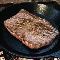 キャンプで鉄板とフライパンで焼いた分厚い肉の写真