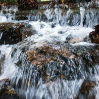岩場を勢いよく流れる小川の水流と飛沫が舞う渓流の写真