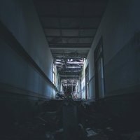 天井が崩落した廃墟の薄暗い廊下の写真