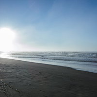 打ち寄せる波と夏の日差しが輝く砂浜でのビーチシーンの写真