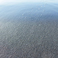 打ち寄せた波が砂浜に引く瞬間の海岸風景と白い泡の写真