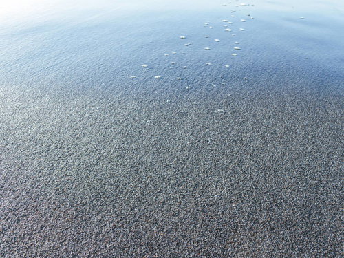 打ち寄せた波が砂浜に引く瞬間の海岸風景と白い泡