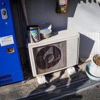 自販機の隣に置かれた古い室外機の写真