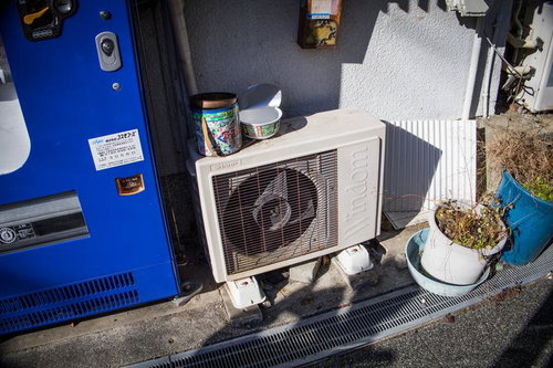 自販機の隣に置かれた古い室外機