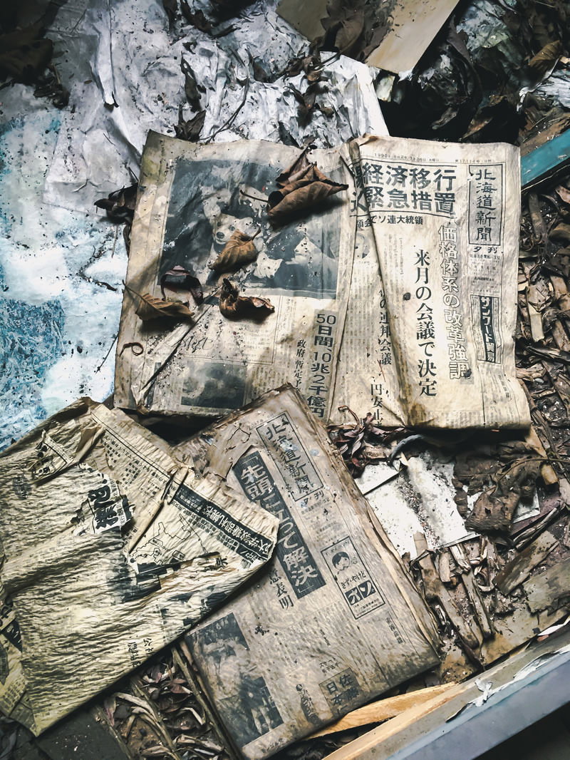 地面に散乱し、ボロボロになった状態で不法投棄された新聞紙
