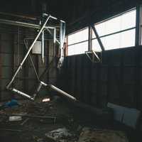 廃墟に差し込む窓の光と散乱する瓦礫と朽ちた配管の写真