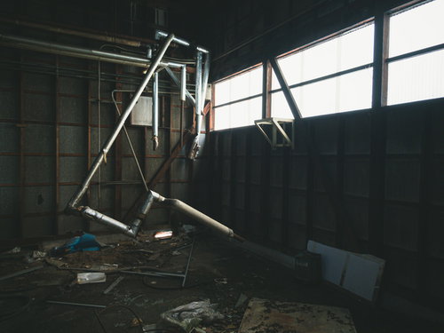 廃墟に差し込む窓の光と散乱する瓦礫と朽ちた配管