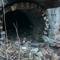崩れ落ちた煉瓦と瓦礫が散乱する古いトンネル通路の写真