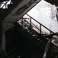 剥き出しの階段と崩れ落ちた柱が残る廃墟の建物跡の写真