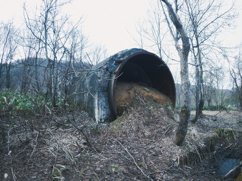 コンクリートトンネルの開いた口から流れ出す土砂