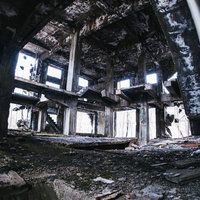 朽ち果てたコンクリート剥き出しの躯体と露出した鉄筋骨組みの写真