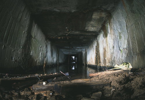 荒廃したコンクリートの空洞に溜まる水と劣化した床