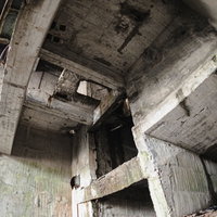 剥がれ落ちたコンクリート躯体が露出した荒廃した建物内部の写真