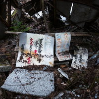 荒廃した瓦礫に置かれた白い御札と朽ちた木材の写真