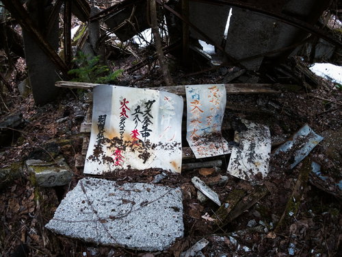 荒廃した瓦礫に置かれた白い御札と朽ちた木材