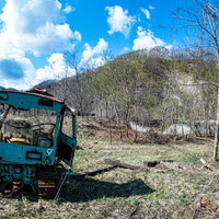 荒地に放置された青いブルトーザーの後ろ姿の写真