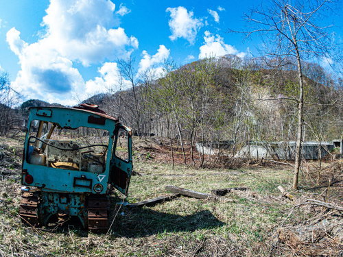 荒地に放置された青いブルトーザーの後ろ姿