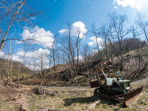 青空の下に放置された錆びついたボロボロのブルトーザー