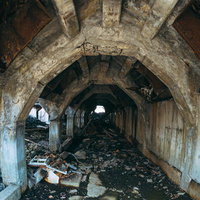 アーチ状の通路に散乱する瓦礫と劣化した躯体の写真