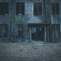 不気味に口を開ける廃墟の入口と複数の窓がある古い建物の写真