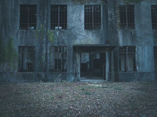 不気味に口を開ける廃墟の入口と複数の窓がある古い建物
