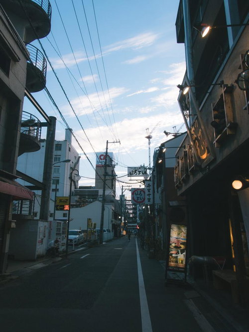 日が落ちてきた商店街の町並み、夜間照明と街灯が点灯する夕暮れの風景