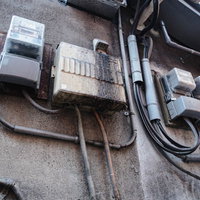 室外に設置された老朽化した電気メーターと分電盤の写真