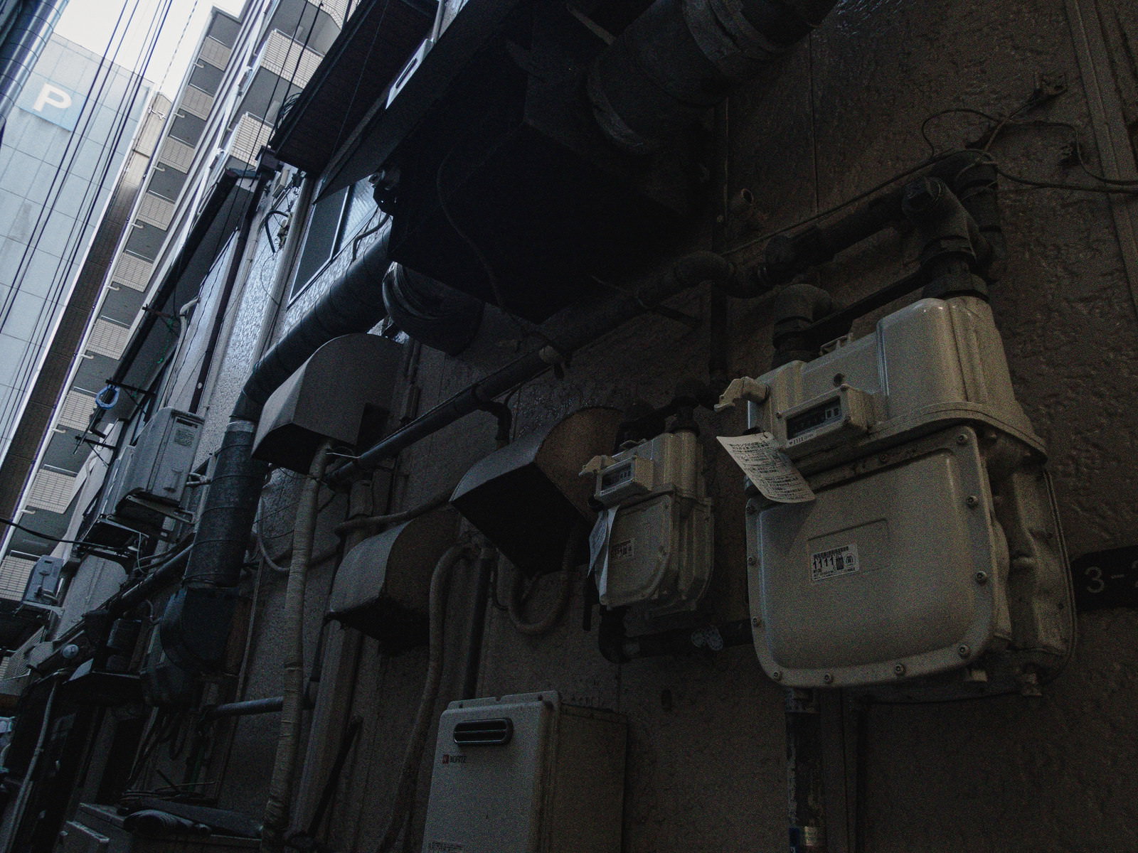 建物の外壁に設置された白いガスメーターと排気ダクト、配管類