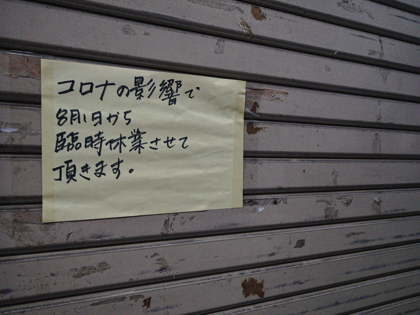 木製シャッターに貼られた手書きの臨時休業お知らせ張り紙