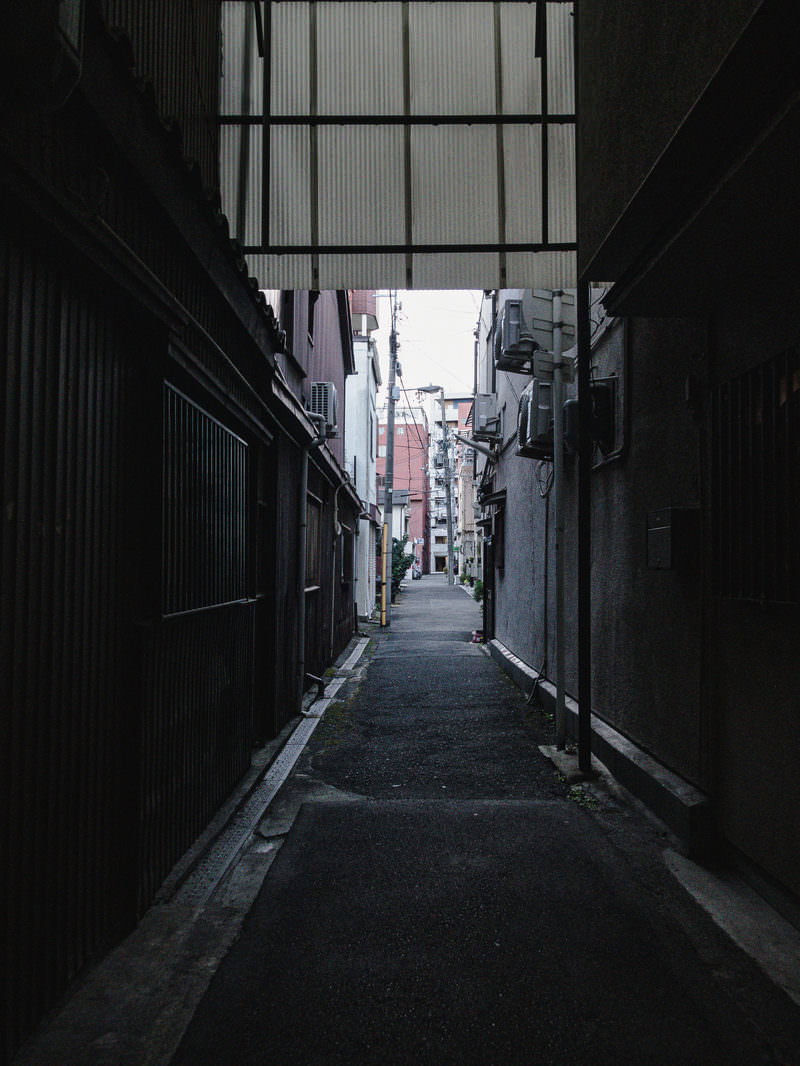 玉造日之出通商店街の薄暗い路地裏、両脇に建物が立ち並ぶ細い通路