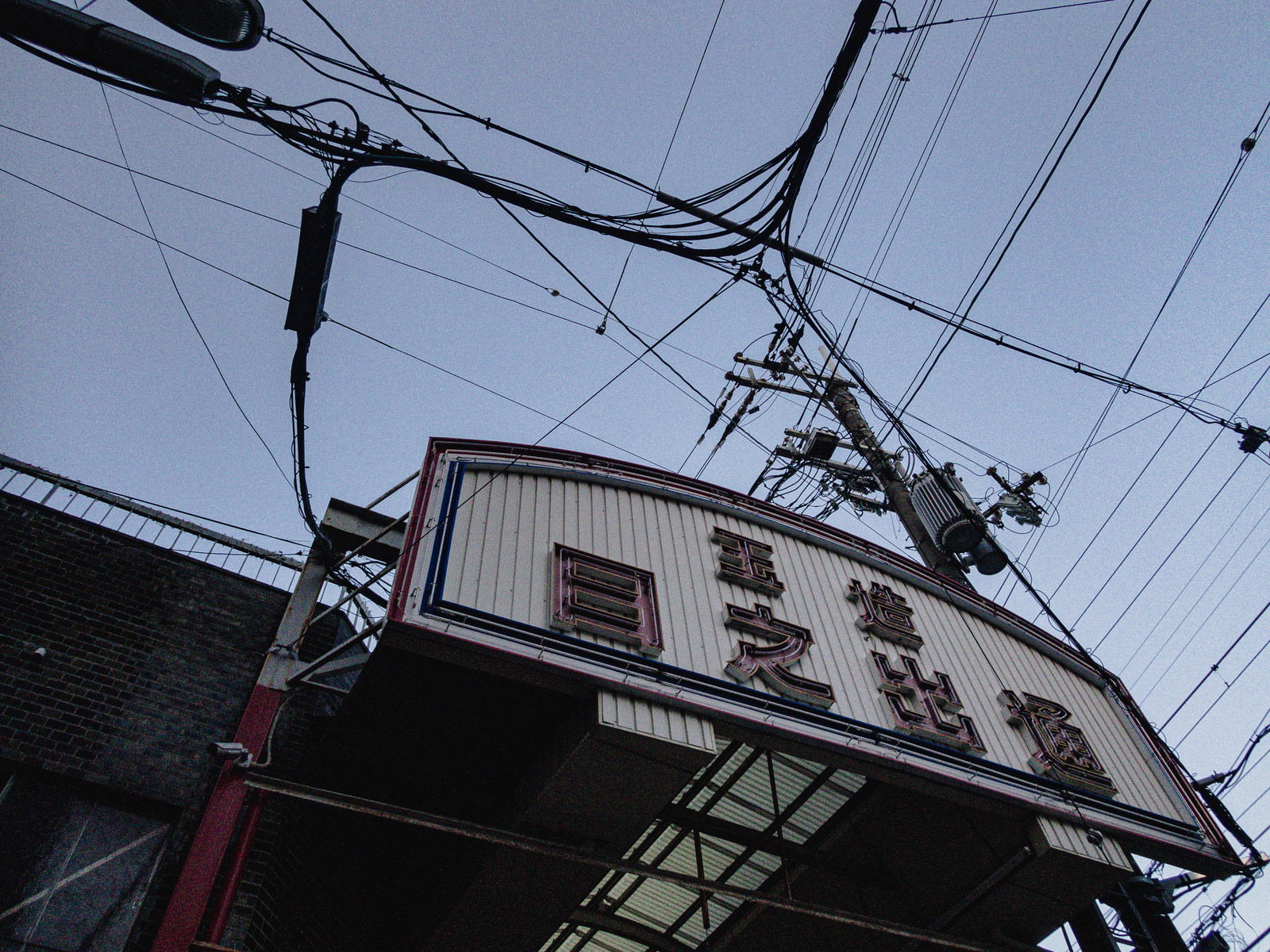 玉造日之出通商店街のアーケード入口にある白い看板と電線