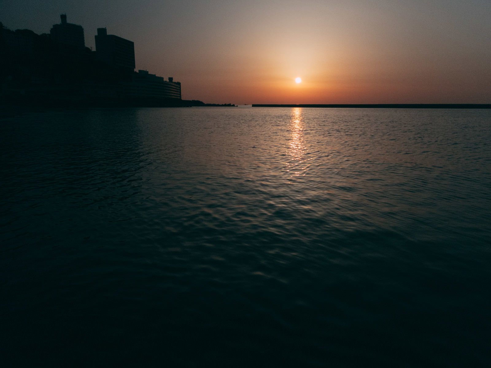 熱海の海に沈む夕日とオレンジ色の夕焼け空、水面に映るレイライン