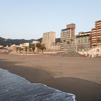 熱海の海岸に打ち寄せる波とホテル群の観光風景の写真