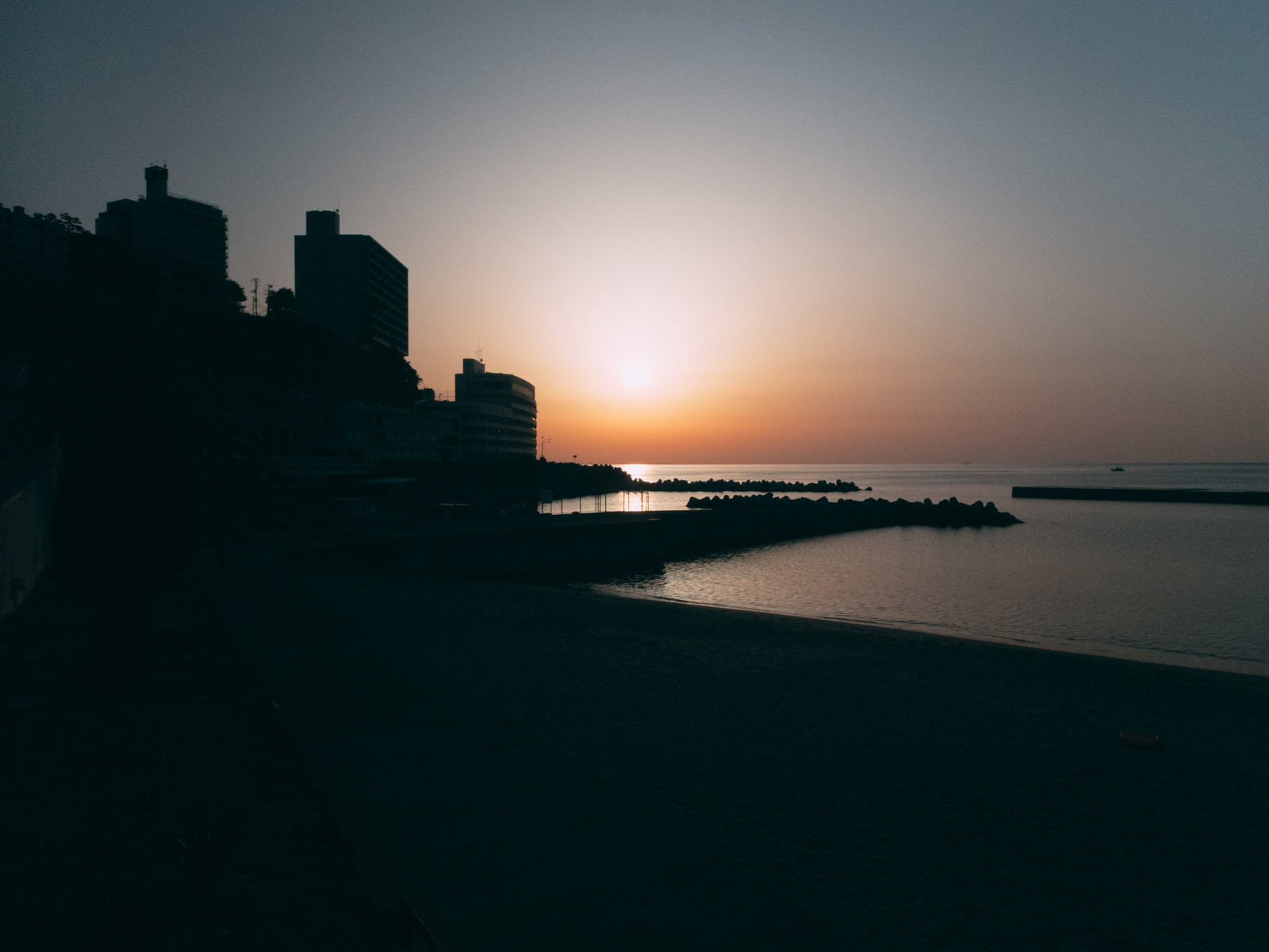 熱海の海に沈む夕日と建物のシルエットが美しい風景