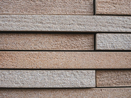 石材タイルの微妙な高さの違いが立体感を生み出す壁