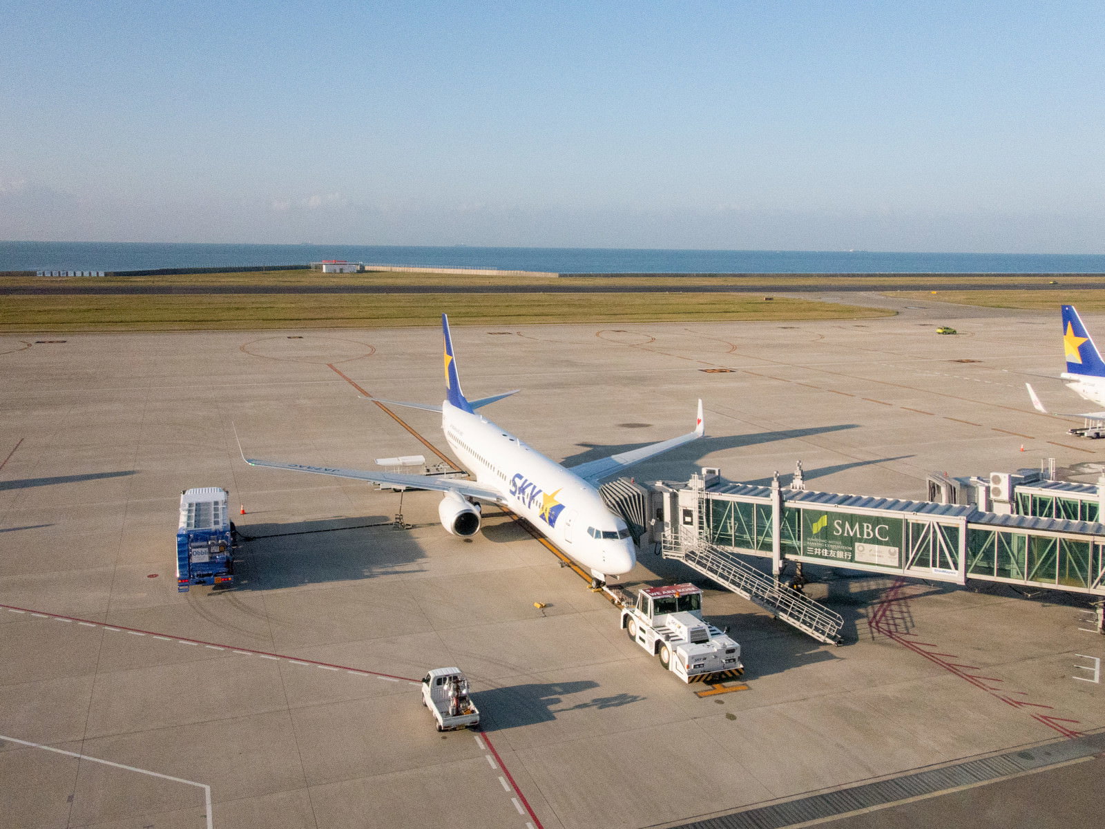 関西空港の滑走路に駐機している白い旅客機と地上作業車両