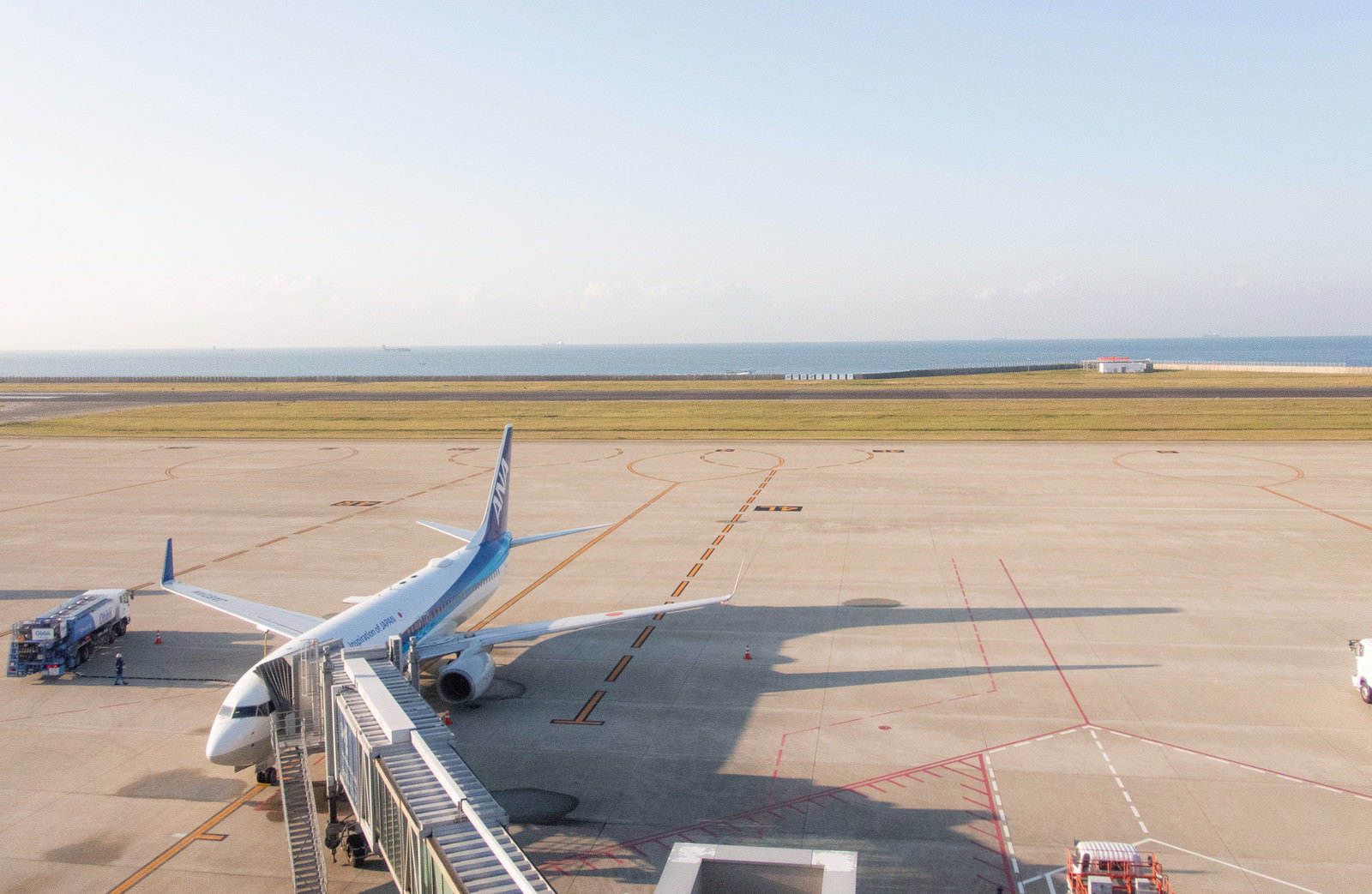 関西空港の滑走路に駐機している白い旅客機と空港施設の風景