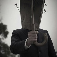 傘を手渡す紙袋を被った紳士のモノクロの写真