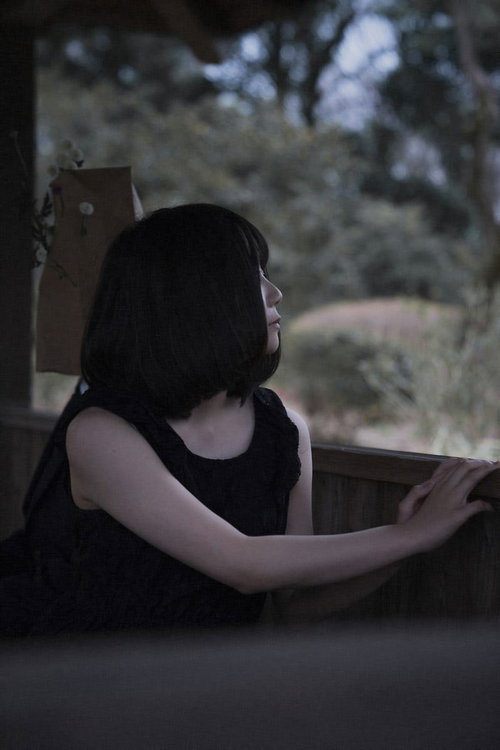 窓辺で外を見つめる闇系女子の横顔、暗い室内で物思いにふける