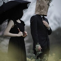 紙袋を被った男性と黒衣の女性が向かい合う人と異形の恋の写真