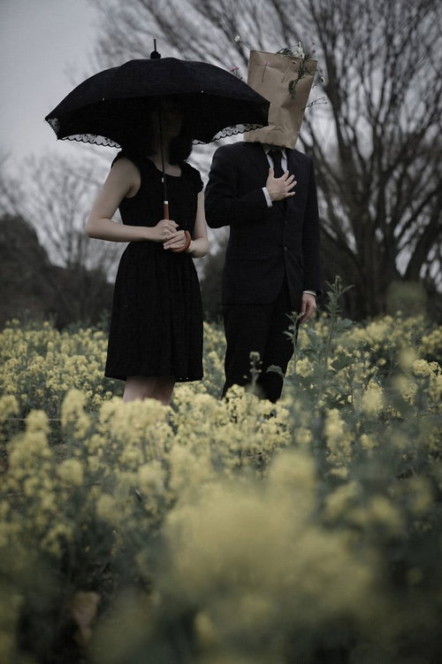 菜の花畑で傘をさすカップル