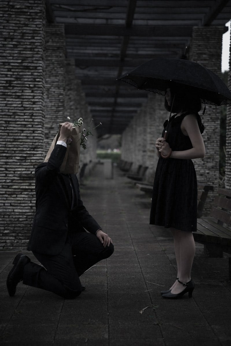 薄暗いレンガ造りの室内で黒いドレスを着た女性たちが立っている
