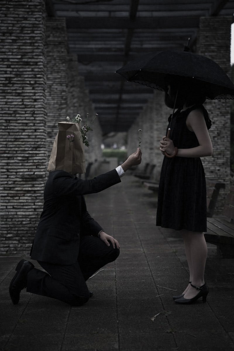 紙袋を被った男性が女性にお花を手渡している様子