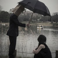 傘を差し上げますよ、雨の中の親切な男性と女性の写真